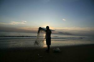 the beauty of the sunset on the beach with the silhouette of a fisherman photo