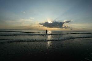 the beauty of the sunset on the beach with the silhouette of a fisherman photo