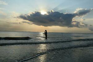 the beauty of the sunset on the beach with the silhouette of a fisherman photo