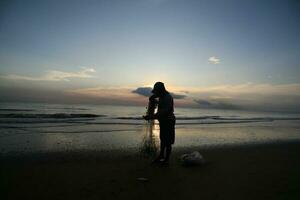 the beauty of the sunset on the beach with the silhouette of a fisherman photo