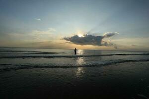 the beauty of the sunset on the beach with the silhouette of a fisherman photo