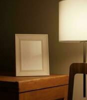 a portrait of little frame mockup in the dark lit by standing lamp on the wooden table photo