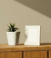 a peace of a little frame mockup poster on the wooden dresser with plant decoration lit by light from the window photo