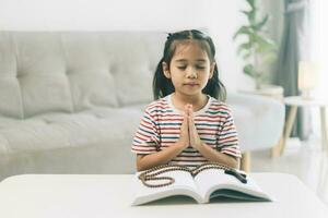 pequeño niña Orando en el mañana.pequeña asiático niña mano manos orando doblada en oración concepto para fe,espiritualidad y religión. foto