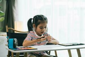 linda asiático niño niña dibujo con color lapices a hogar foto