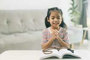 pequeño niña Orando en el mañana.pequeña asiático niña mano manos orando doblada en oración concepto para fe,espiritualidad y religión. foto