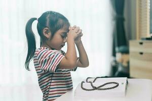 pequeño niña Orando en el mañana.pequeña asiático niña mano manos orando doblada en oración concepto para fe,espiritualidad y religión. foto