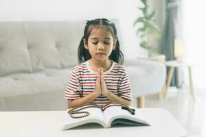 pequeño niña Orando en el mañana.pequeña asiático niña mano manos orando doblada en oración concepto para fe,espiritualidad y religión. foto