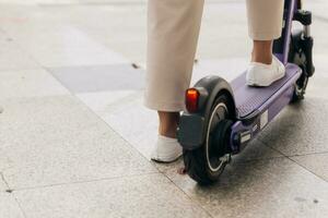 Close-up of woman legs riding electric scooter in the city photo