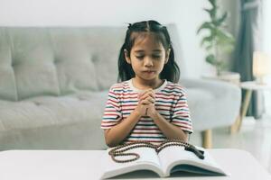 pequeño niña Orando en el mañana.pequeña asiático niña mano manos orando doblada en oración concepto para fe,espiritualidad y religión. foto