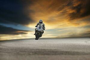 hombre montando deporte motocicleta en hormigón pista en contra hermosa dramático cielo foto