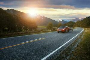 red pick up truck passing on asphalt highway at mount aspiring national park southland new zealand one of most popular traveling destination photo