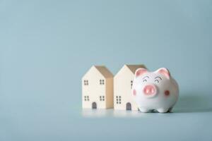 Piggy bank and small wooden house at back concept of savings. Save money to buy , loan , rent the house. photo