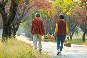 Happy farmer family carrying organics homegrown produce harvest with apple, squash and pumpkin while walking along the country road with fall color from maple tree during autumn season photo