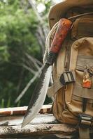 A knife backpack with equipment for survival in the forest on an old timber wooden photo