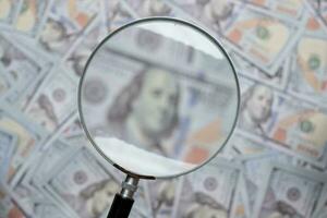 Blurred image of us dollar bill through magnifying lens checking banknotes photo