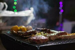 Meat and skewers ingredients for barbecue party are placed on grill to cook barbecue and make it ready for family to join barbecue party tonight.  party background image has Copy Space for text. photo