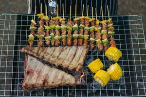 Meat and skewers ingredients for barbecue party are placed on grill to cook barbecue and make it ready for family to join barbecue party tonight.  party background image has Copy Space for text. photo