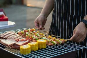 Meat and skewers ingredients for barbecue party are placed on grill to cook barbecue and make it ready for family to join barbecue party tonight.  party background image has Copy Space for text. photo