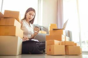 woman checking package of goods from customer online order is alone in her home office as she is an SME entrepreneur and uses her phone and tablet to market online. concept online sales business photo