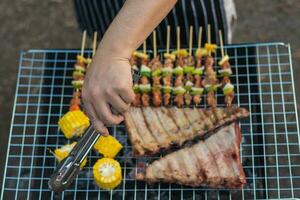 Meat and skewers ingredients for barbecue party are placed on grill to cook barbecue and make it ready for family to join barbecue party tonight.  party background image has Copy Space for text. photo