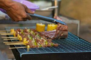 Meat and skewers ingredients for barbecue party are placed on grill to cook barbecue and make it ready for family to join barbecue party tonight.  party background image has Copy Space for text. photo