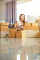 woman checking package of goods from customer online order is alone in her home office as she is an SME entrepreneur and uses her phone and tablet to market online. concept online sales business photo