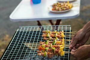 Meat and skewers ingredients for barbecue party are placed on grill to cook barbecue and make it ready for family to join barbecue party tonight.  party background image has Copy Space for text. photo