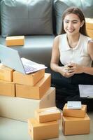 woman checking package of goods from customer online order is alone in her home office as she is an SME entrepreneur and uses her phone and tablet to market online. concept online sales business photo