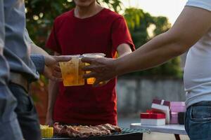 Beer drinks prepared for barbecue party among friends are served in plastic glasses because plastic glasses can be easily stored at end of party. Easy party idea by serving beer in plastic glasses. photo