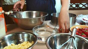 Nahansicht Einweichen Blatt Gelatine im kalt Wasser. Hausfrau Stehen beim Küche Tabelle mit Zutaten zum Herstellung köstlich hausgemacht Kuchen. Süßwaren. kulinarisch. Prozess von vorbereiten Süss Mousse Dessert video