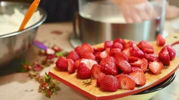 Focus on delicious organic sliced strawberries on the wooden board on kitchen table over the background of removable cake mold and fresh ingredients. Culinary. Confectionery. Sweet dessert. Gourmet video