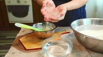 Close-up pregnant female chef taking soaked swollen leaf gelatin out of a bowl with water, squeezing the excess of water and putting it into a metal bowl with melted white confectionery chocolate video