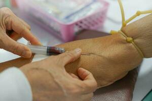 puncture of a vein through the skin in order to withdraw blood for analysis.the specialist uses a syringe to venipuncture from patient's arm. selective focus photo