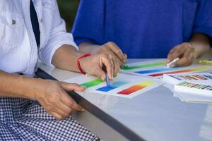 asian female art teacher teaching a teenage boy student in basic crayons drawing in school art class,adult help teen in school art club photo