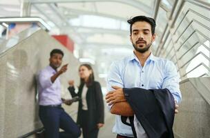 young executive standing with arms crossed, background are employee talking about him as bullying photo