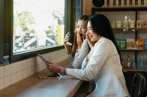 young business women looking something on computer tablet smiling and wow face while working casually in a coffee shop. photo