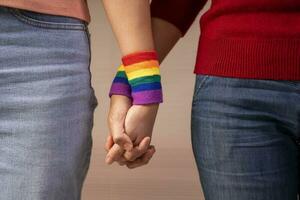 romantic lesbian lover wear lgbt rainbow wristband hands holding support each others, concept of lgbtq community equality movement, lgbtq happy pride month photo