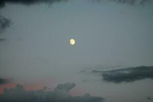 The moon glows in the evening sky photo