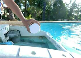 Hand holding a tablet chlorine into filtration . chlorine tablet for pool water cleaning and maintenance. photo