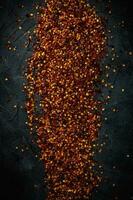 Crushed dried flackes red pepper from top on dark background photo