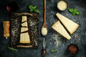 Piece of Parmesan cheese and cheese knife. On a dark background. Traditional Italian cheese. Top view. Copyspace photo
