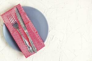 Empty plate, knife, fork and napkin over white table background. View from top with copy space photo