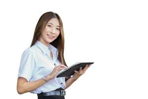 Portrait of an Asian Thai girl student in a uniform is standing smiling happily and confidently while using a tablet isolated on white background. photo