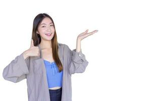 Beautiful young Asian woman wearing a purple shirt is acting thumb up as a good symbol and another hand shows as presenting something on the background. photo