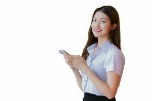 Portrait of an Asian Thai woman student in a uniform is smiling happily while using a smartphone at university with brick walls as a background. photo