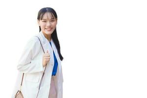 Confident young Asian woman who wears a white shirt and shoulder bag smiles happily while she is walking to work at office isolated on white background. photo