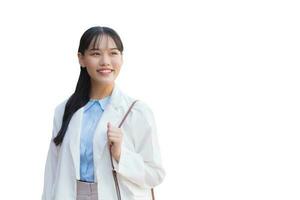 Confident young Asian female who wears white shirt and shoulder bag smiles happily while she is walking to work at office isolated on white background. photo