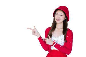 Pretty Asian woman who wears red coat and white hat as santy girl acts her hand to present something isolated on white background. photo