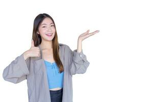 Beautiful young Asian woman wearing blue shirt is acting thumb up as good symbol and another hand shows as presenting something while isolated on white background. photo